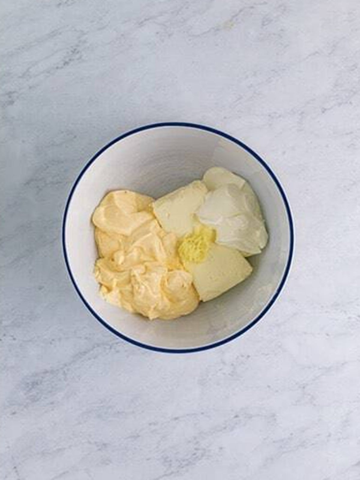 Mayonnaise, cream cheese, and sour cream in a bowl before mixing.