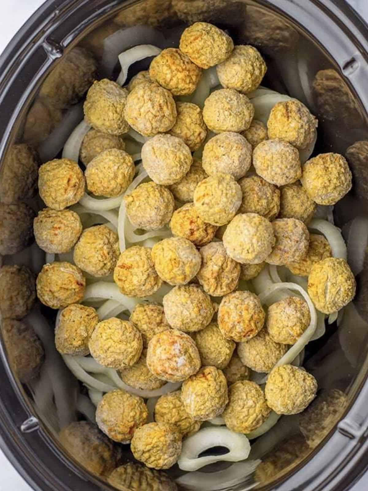 Frozen meatballs and sliced sweet onions layered in a slow cooker.