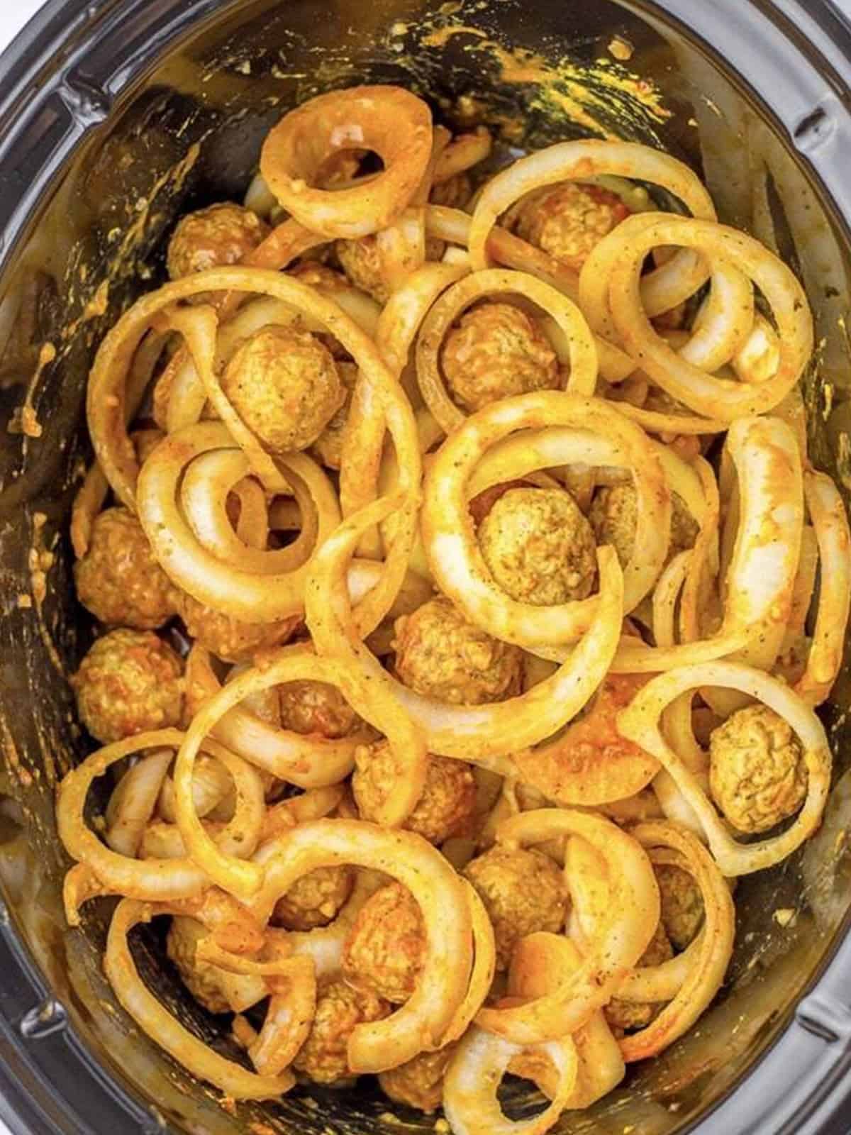 Meatballs and onions stirred together and cooking in the French onion gravy.