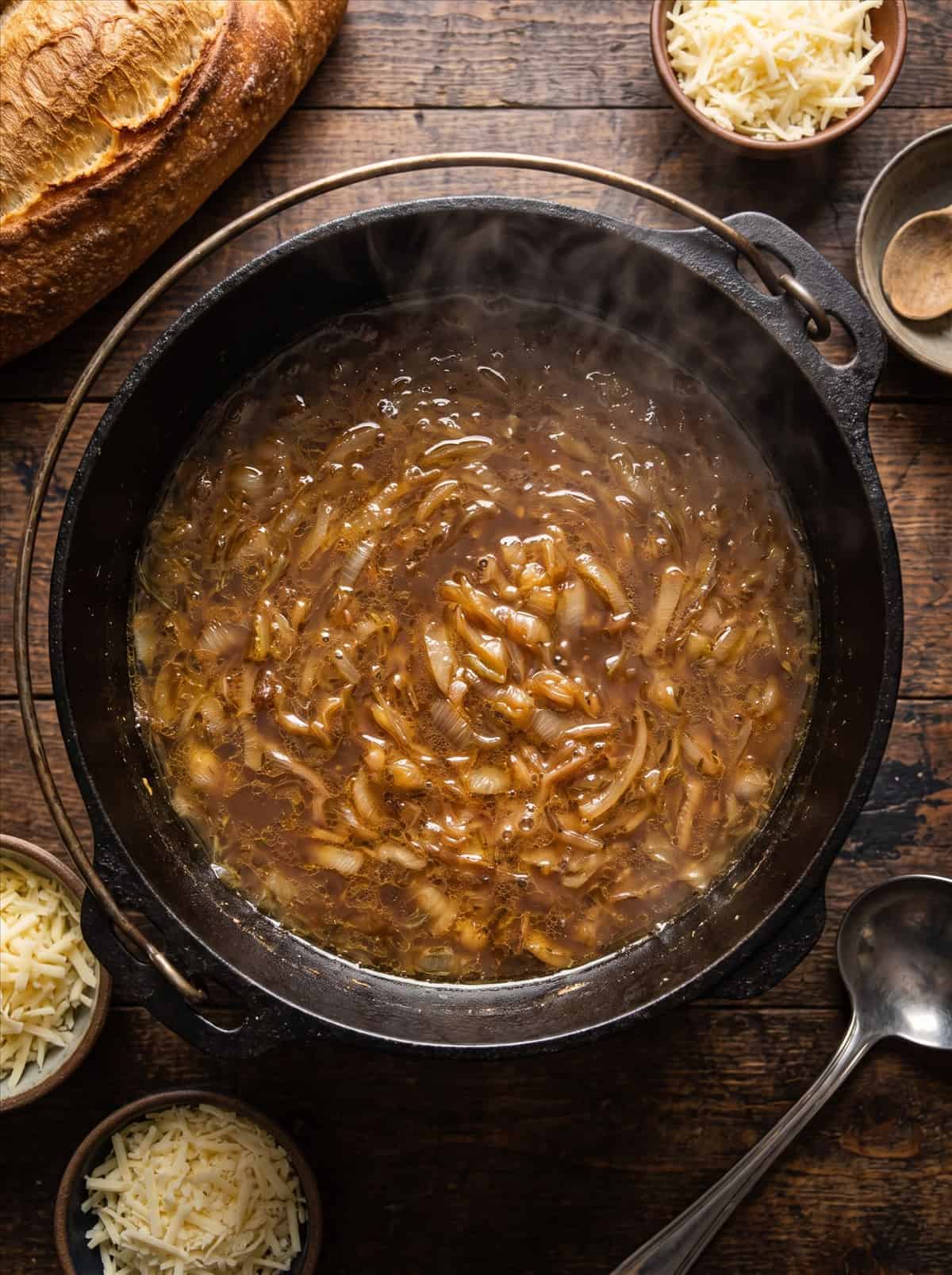 Rich French onion soup broth simmering with caramelized onions in a Dutch oven.