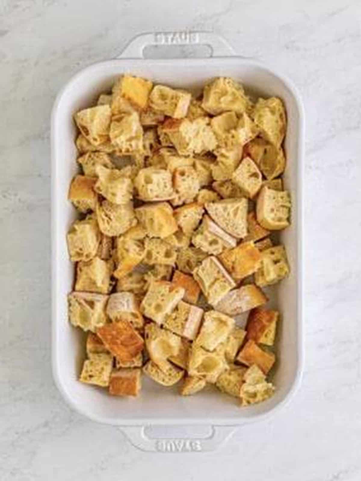 Cubed french bread in a white baking dish.