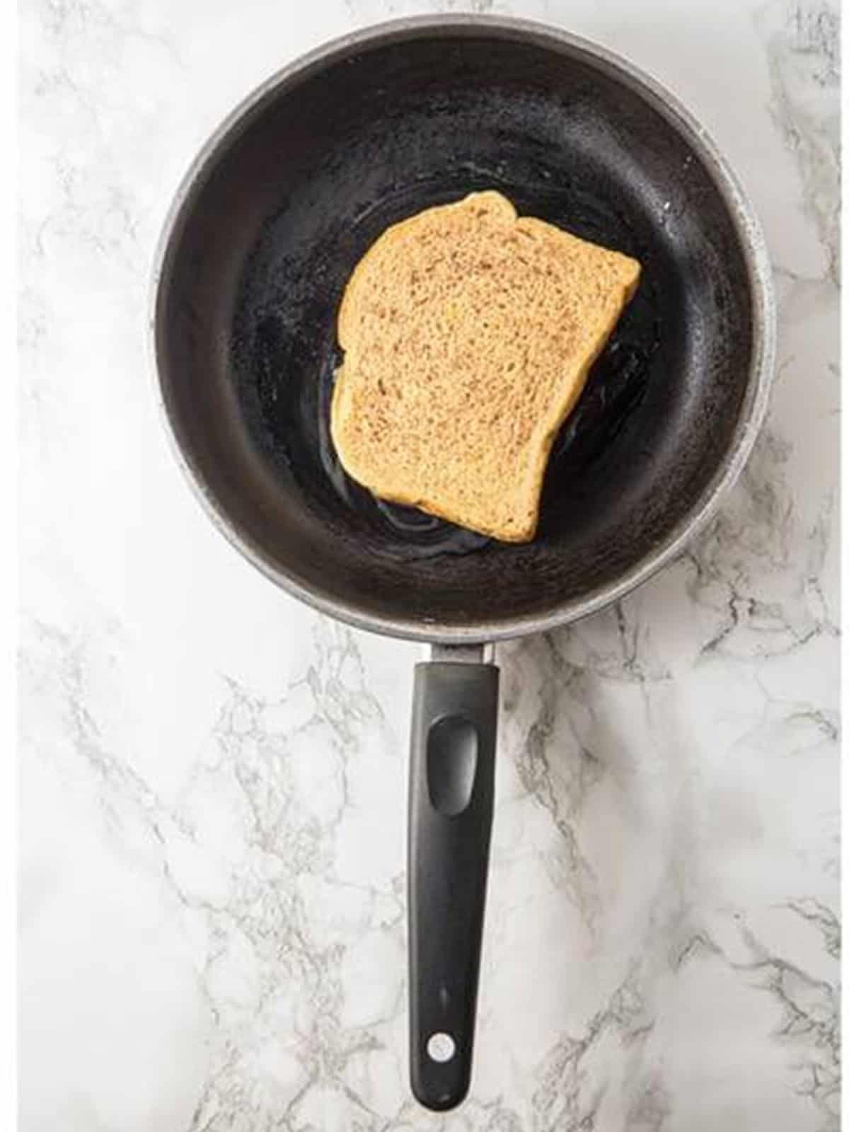 French toast cooking in a buttered skillet until golden on the first side.
