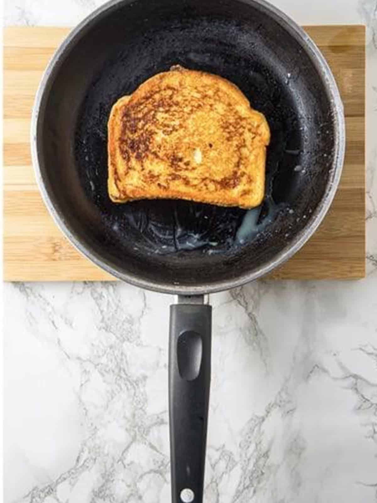 Golden brown French toast flipped and finishing in the skillet.