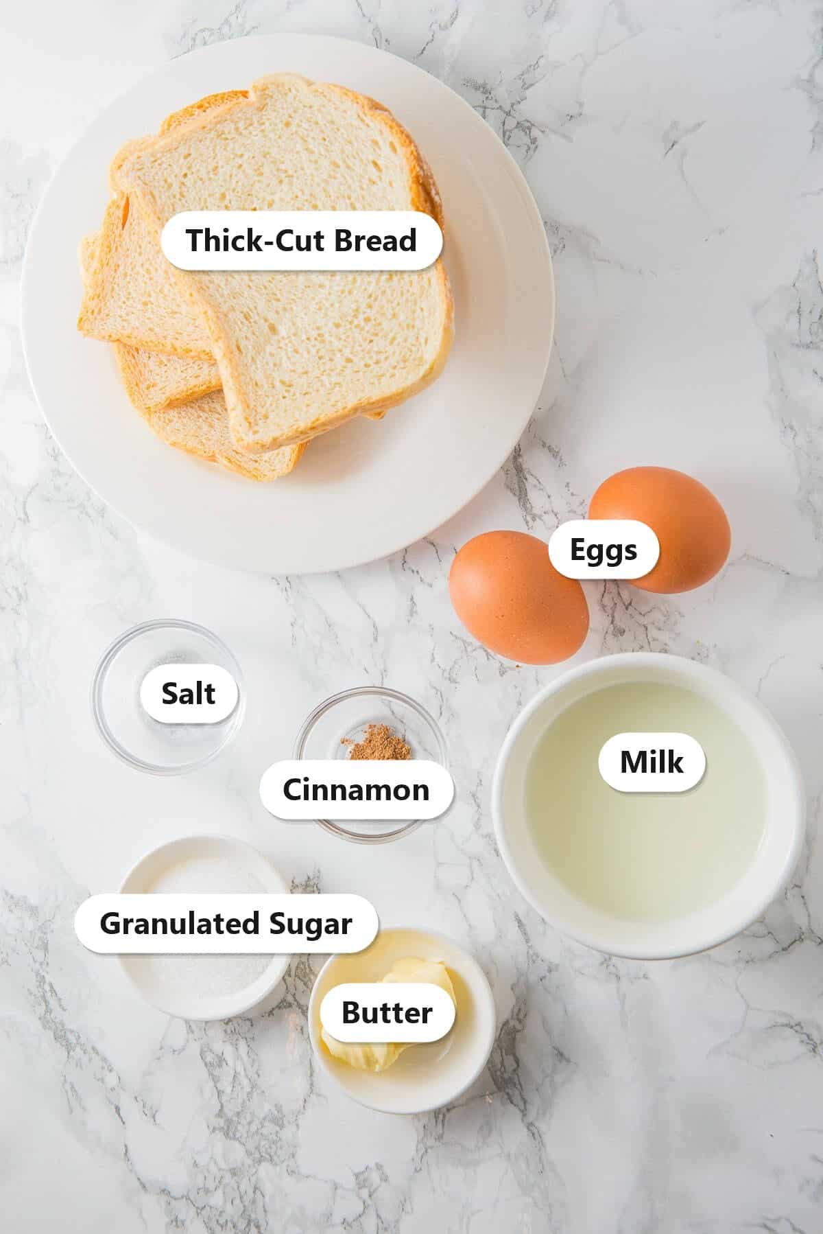 Labeled ingredients for French toast including thick-cut bread, eggs, milk, granulated sugar, cinnamon, salt, and butter.