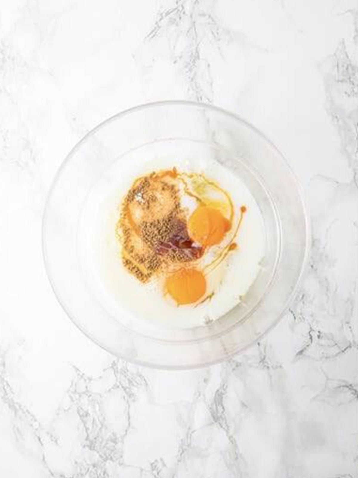 Eggs and milk being whisked together in a glass bowl for French toast custard.