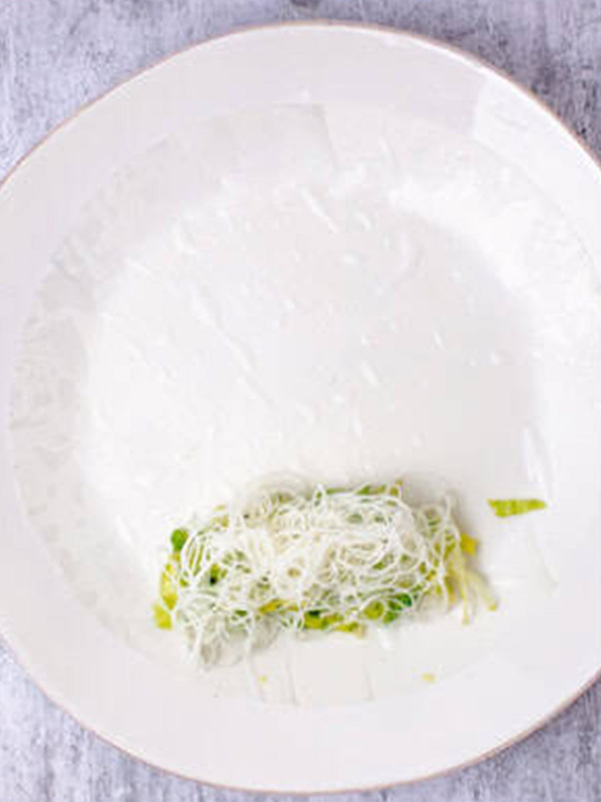 Rice noodles layered over the lettuce on a rice paper wrapper.