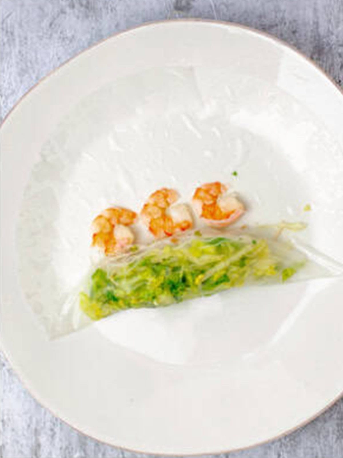 Cooked shrimp laid along the fold of the rice paper wrapper.