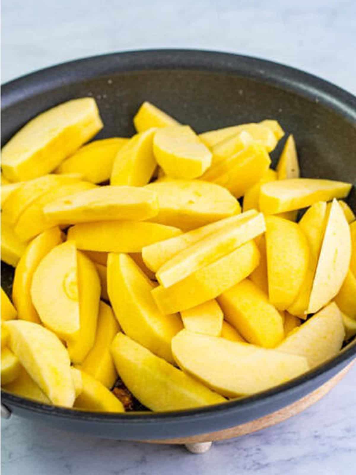Sliced Golden Delicious apples added to the buttery cinnamon sugar in the skillet.