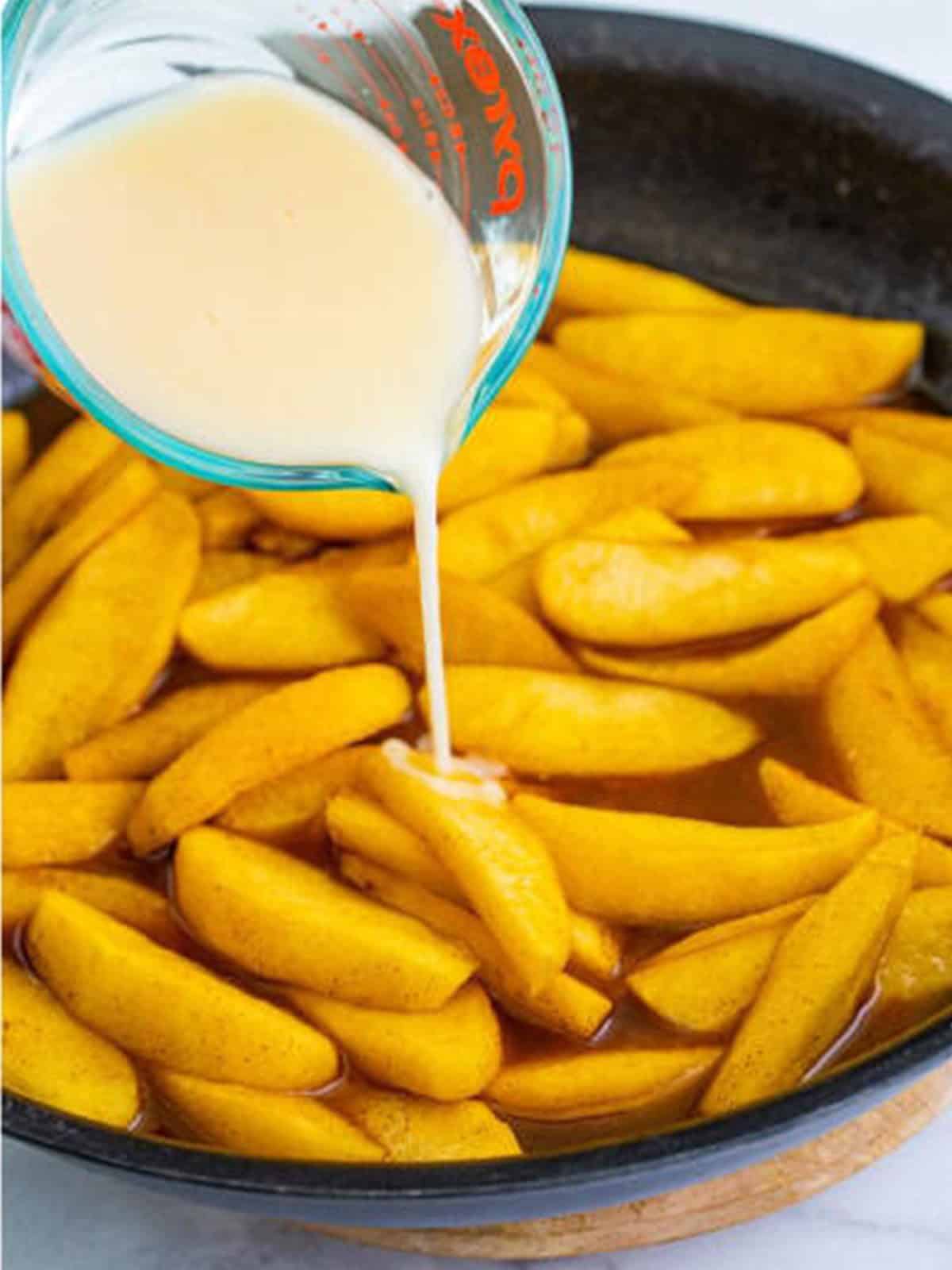 The cornstarch slurry being poured into the simmering fried apples.
