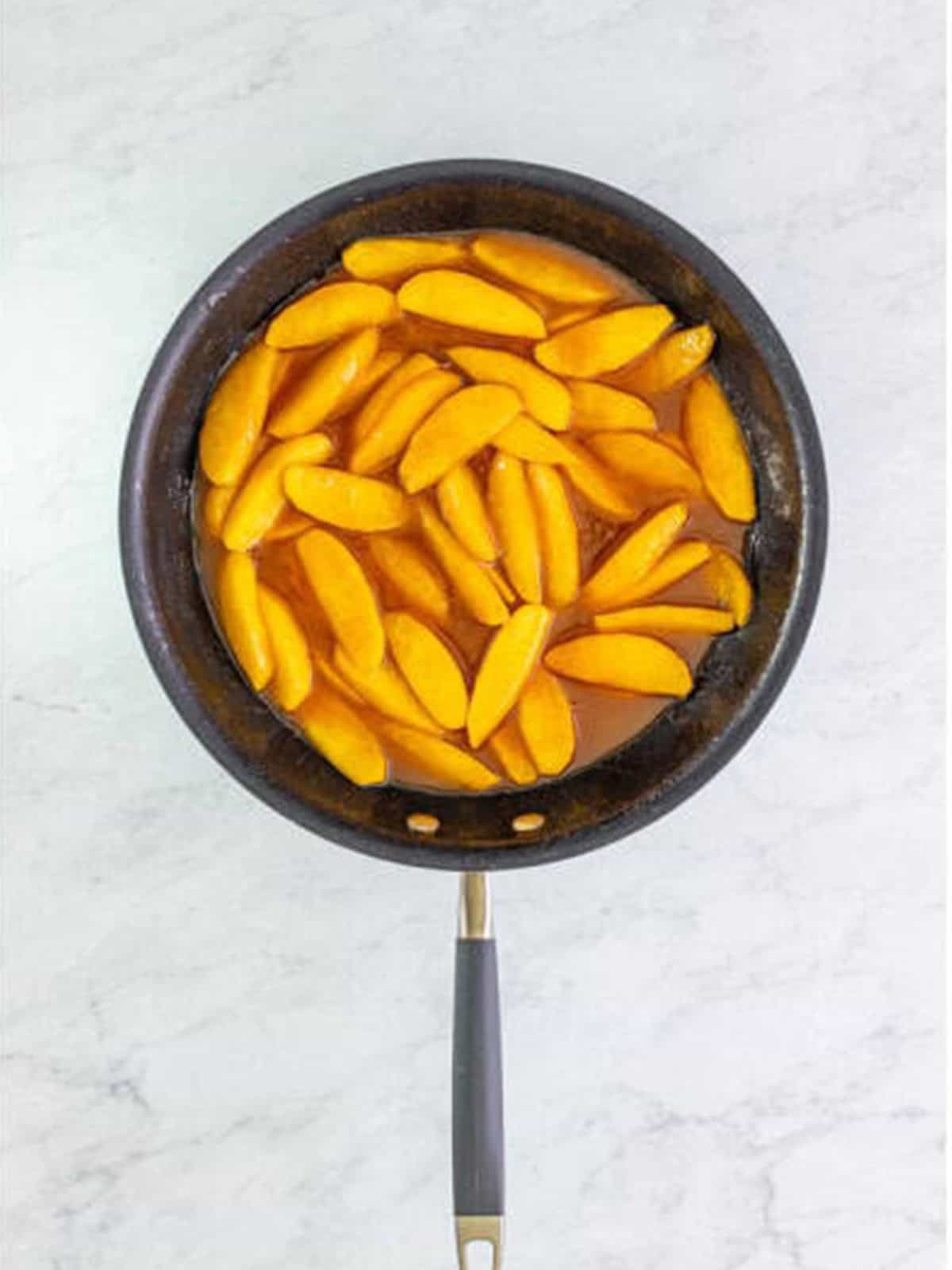 Finished fried apples thickened in a glossy cinnamon sauce in the skillet.