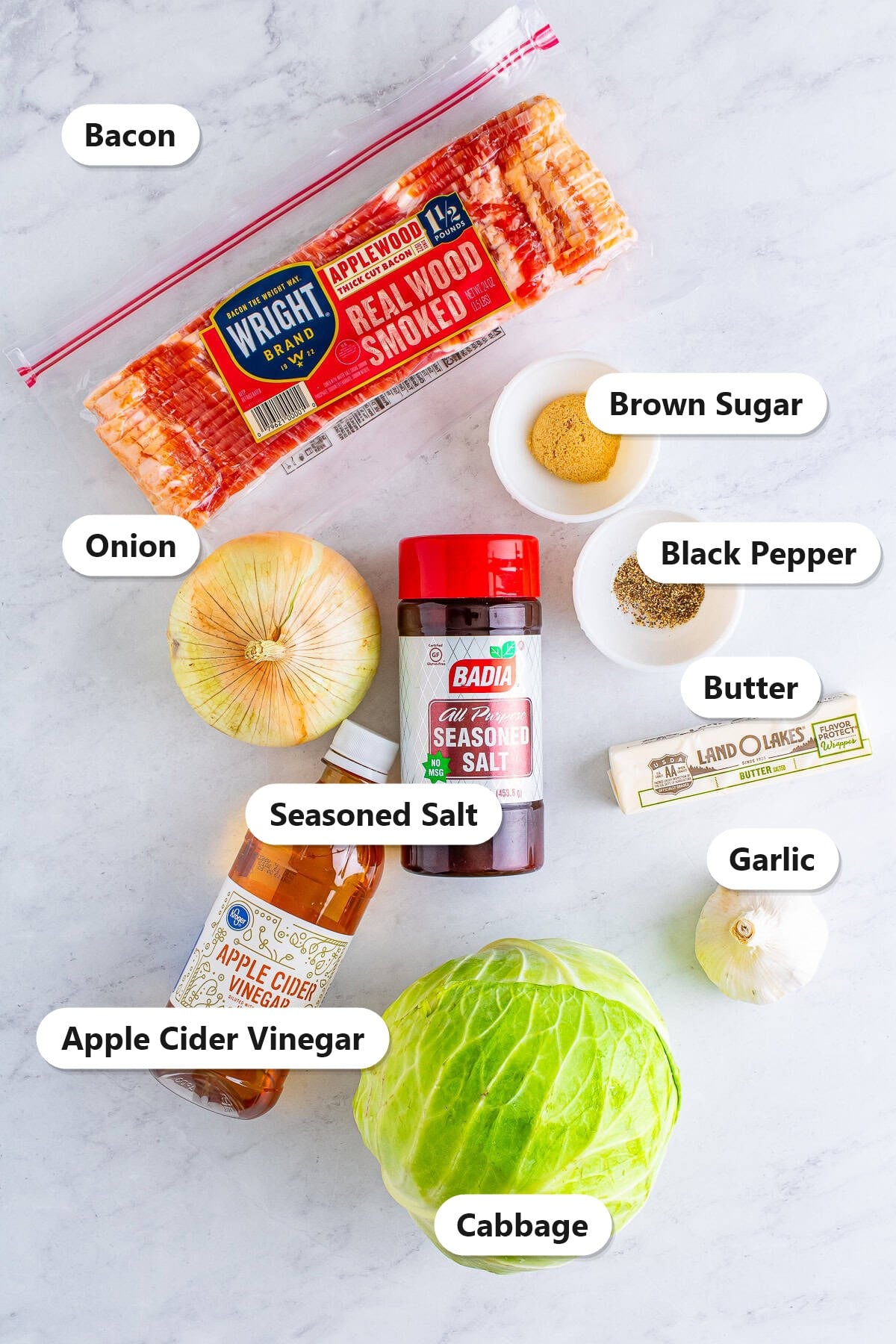 Labeled ingredients for southern fried cabbage including bacon, cabbage, onion, garlic, apple cider vinegar, brown sugar, seasoned salt, pepper, and butter.