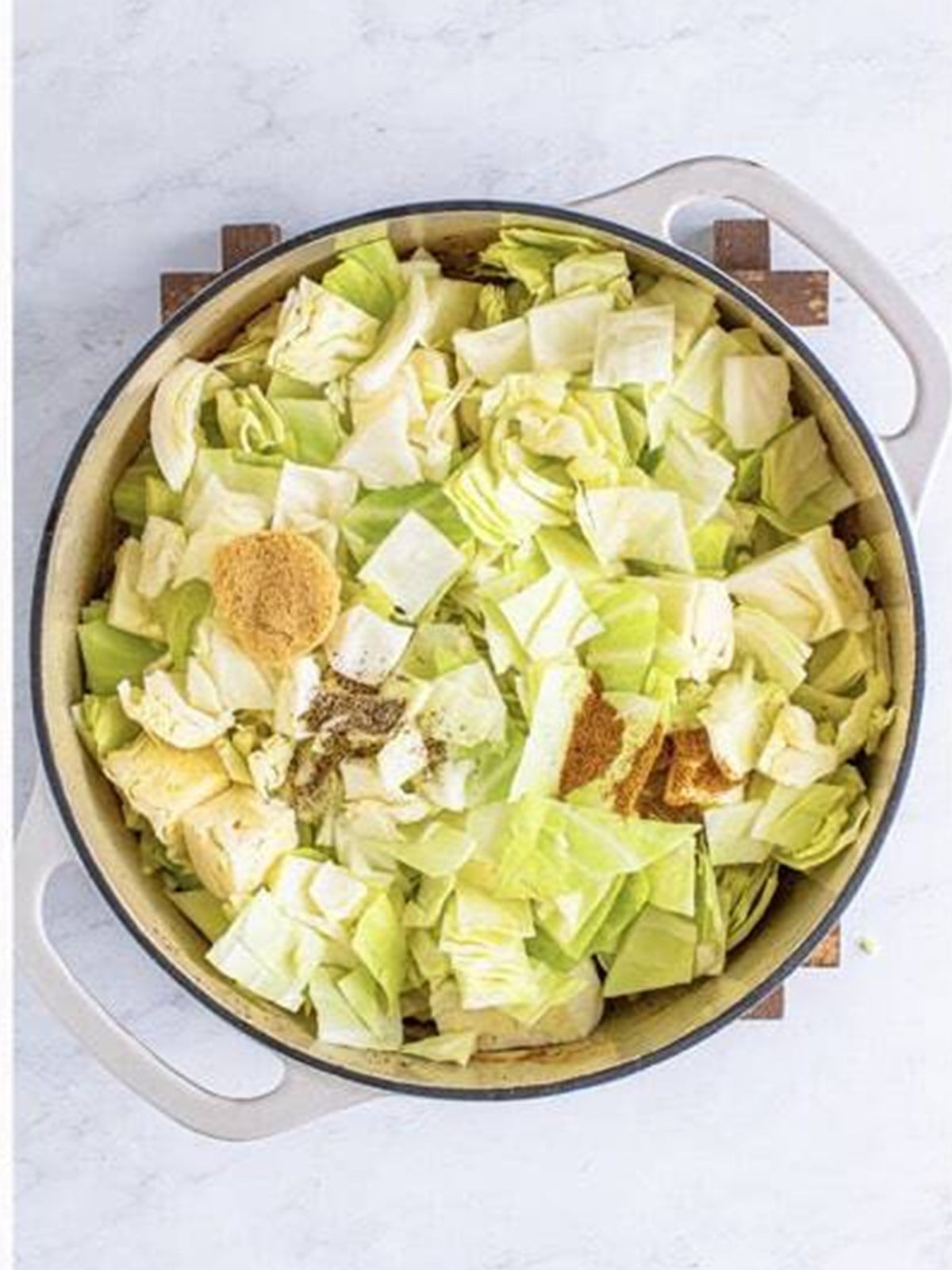 Chopped cabbage added to the onions and garlic in a pot.