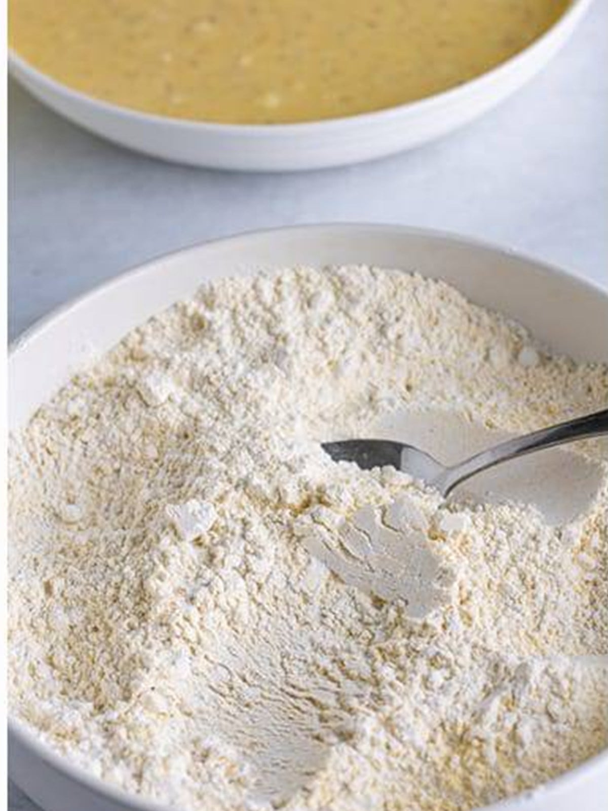 Self-rising flour and cornmeal stirred together in a white bowl.