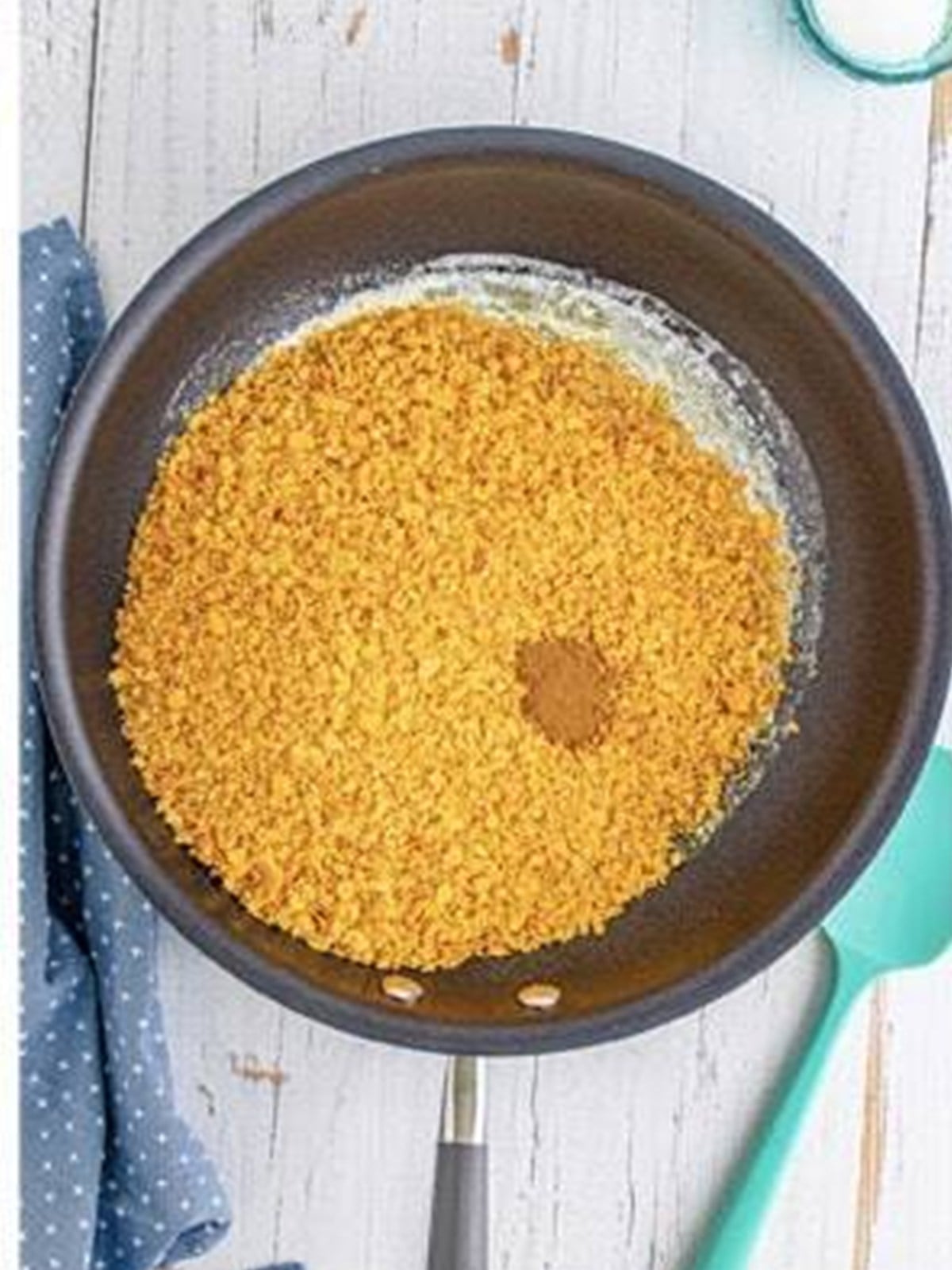 Crushed cornflakes and cinnamon stirred into the melted butter in a skillet.