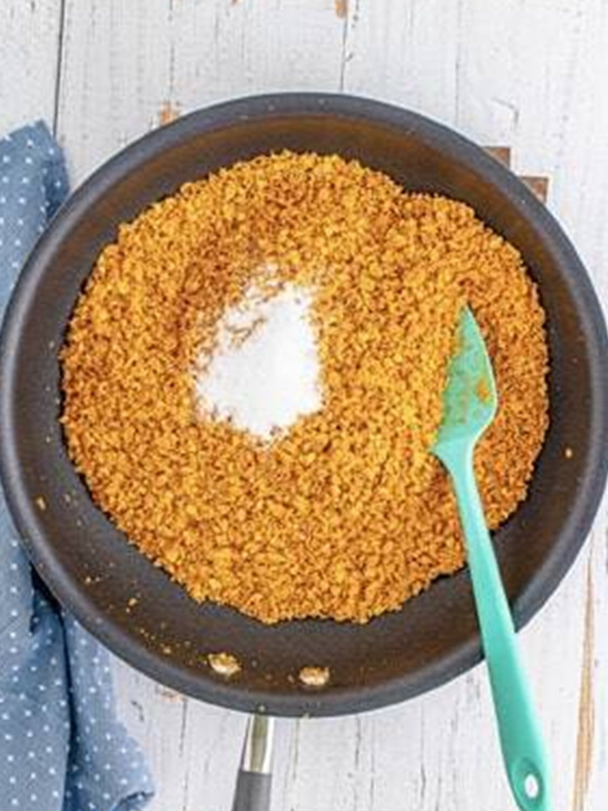 Stirring sugar into the toasted cornflake crumbs in the skillet.