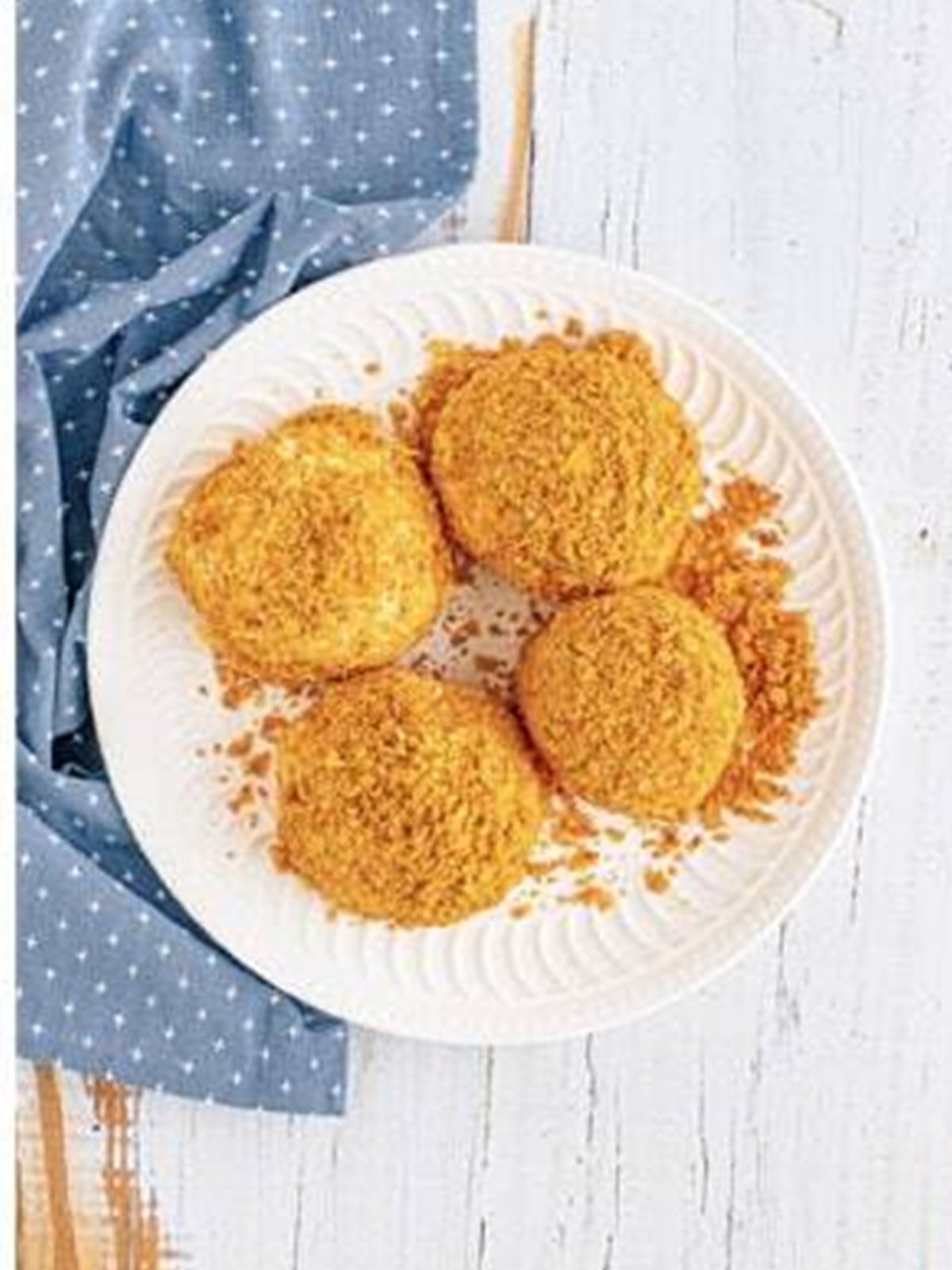 Finished fried ice cream balls coated in cornflake crumbs on a plate.