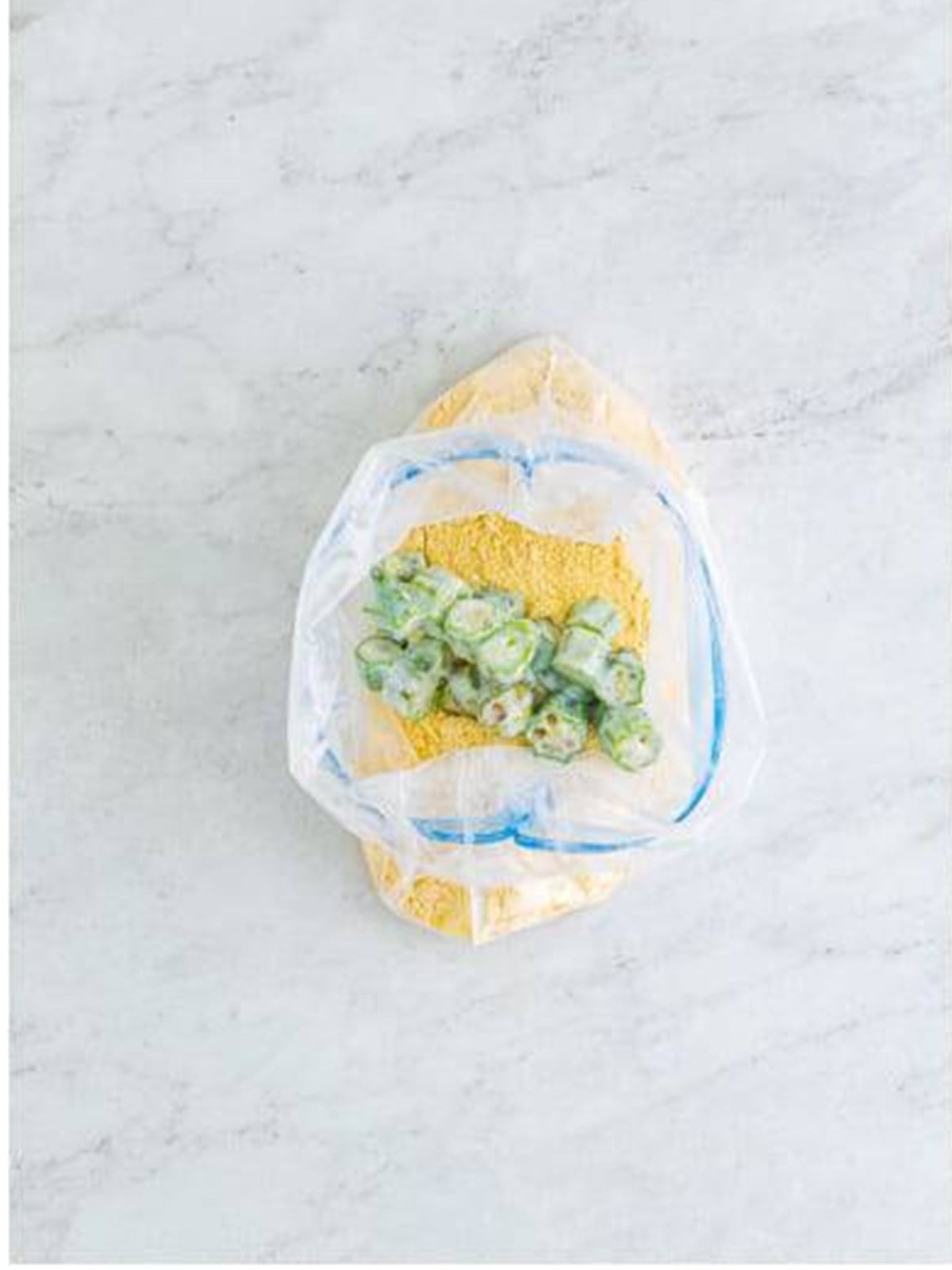 Buttermilk-soaked okra tossed in the cornmeal breading in a bag for fried okra.
