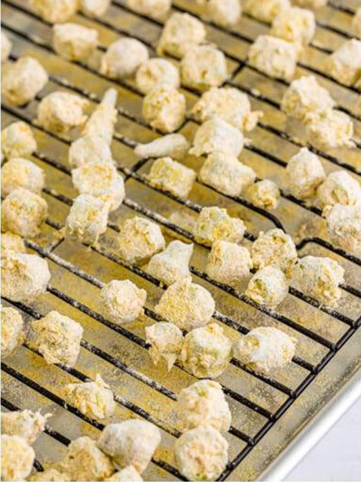 Breaded okra spread out on a wire rack so excess flour falls off before frying.