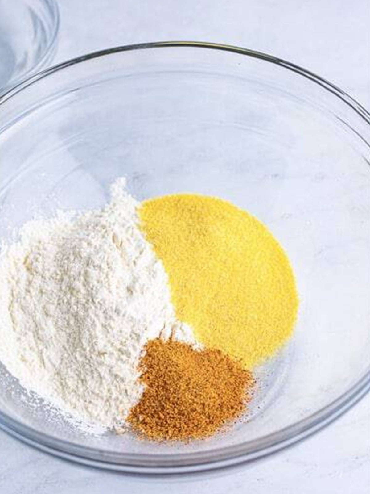 Flour, cornmeal, and Creole seasoning in a glass bowl.