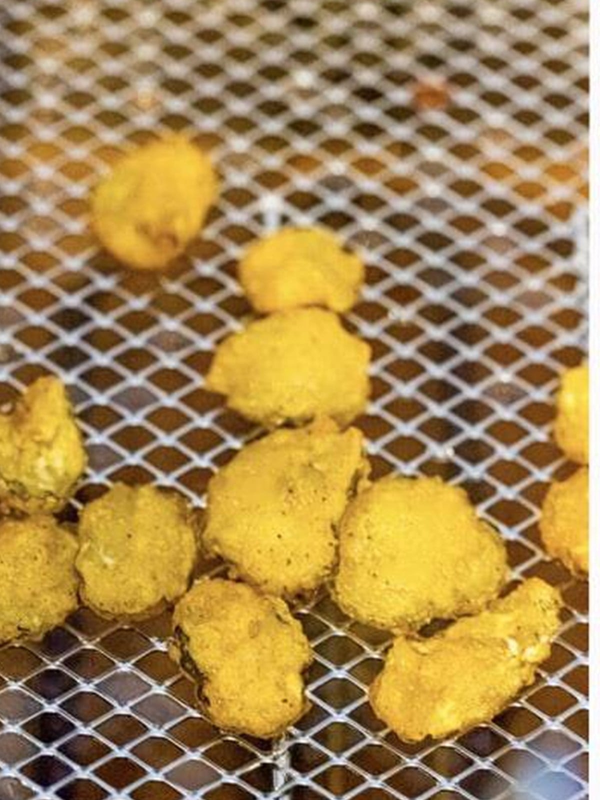 Battered pickle chips dropped into hot oil to fry.