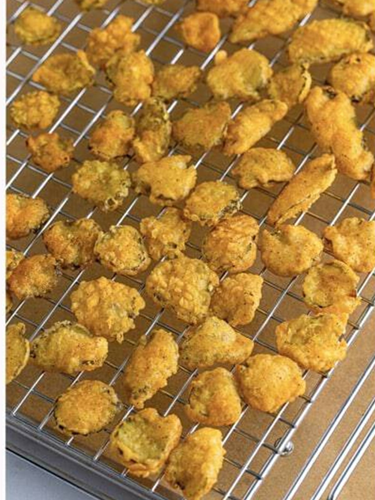 Crispy fried pickles resting on a wire rack before serving.