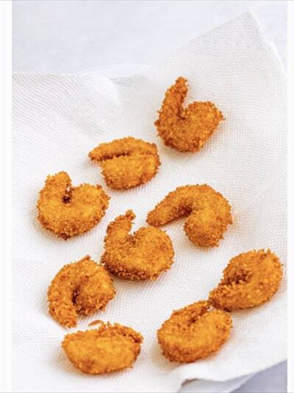 Fried shrimp draining on paper towels.