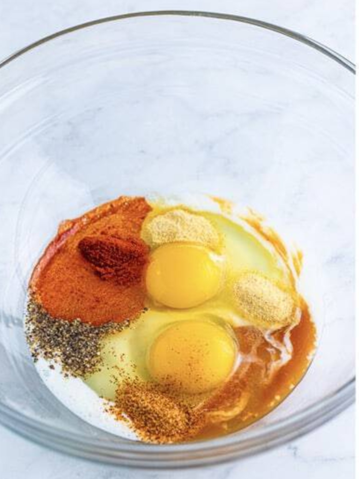 Whisking eggs, buttermilk, hot sauce, and spices into an egg wash for Fried Shrimp.