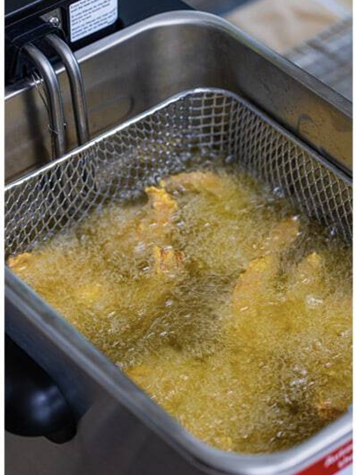 Frying the breaded shrimp in hot oil until golden brown and crispy.