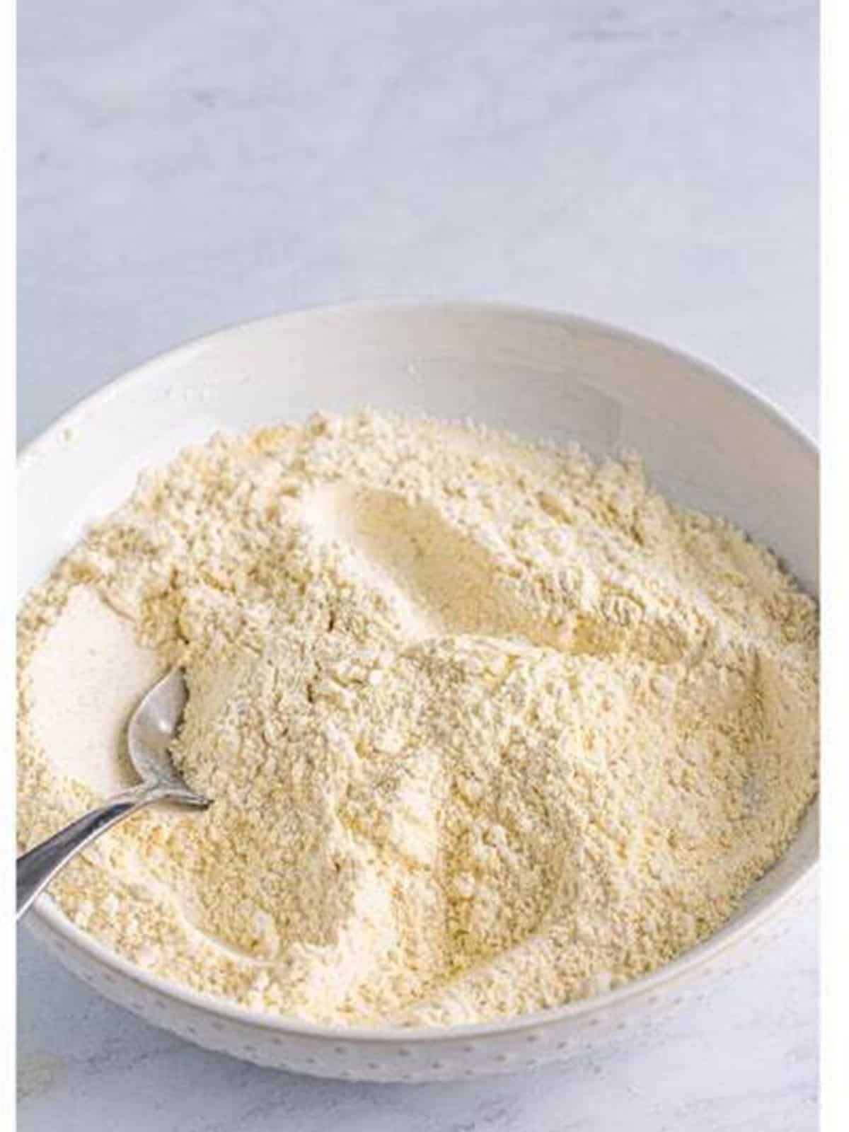 Flour, cornmeal, and seasonings stirred together in a shallow dish.