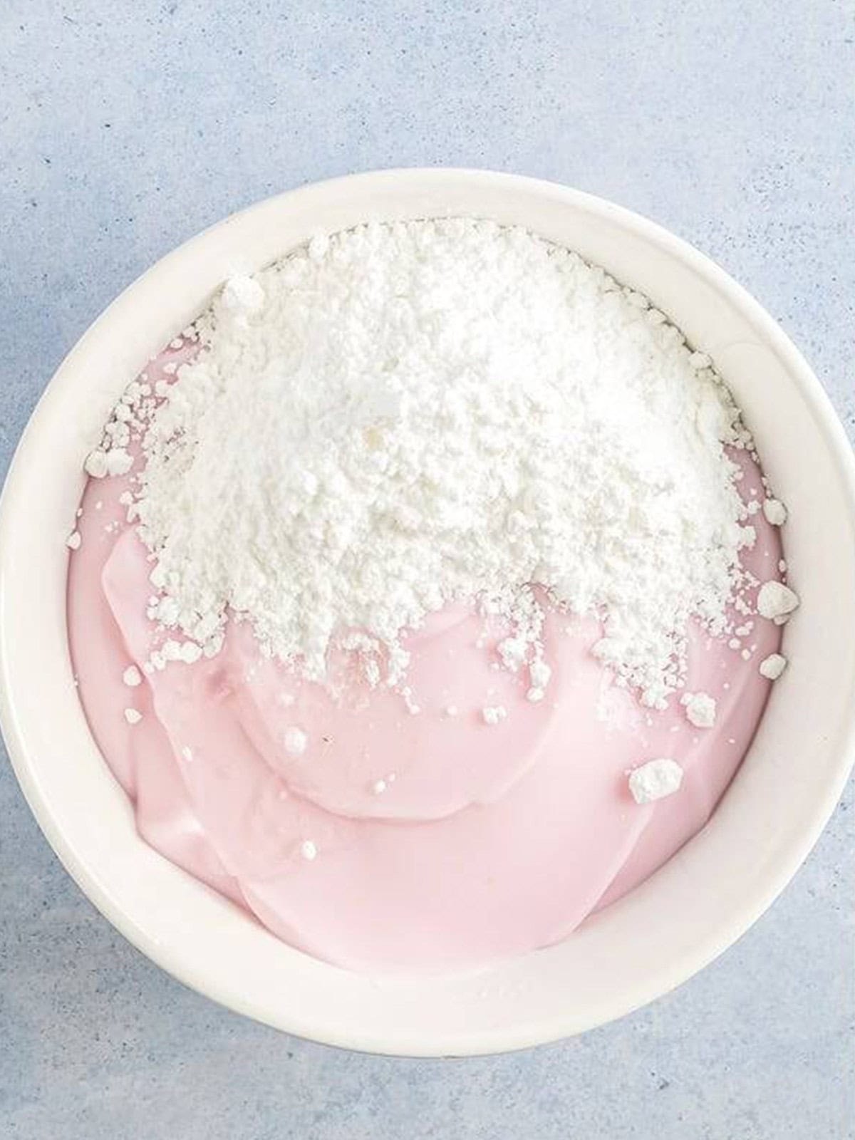 Yogurt and powdered sugar in a white bowl ready to mix for frozen yogurt.