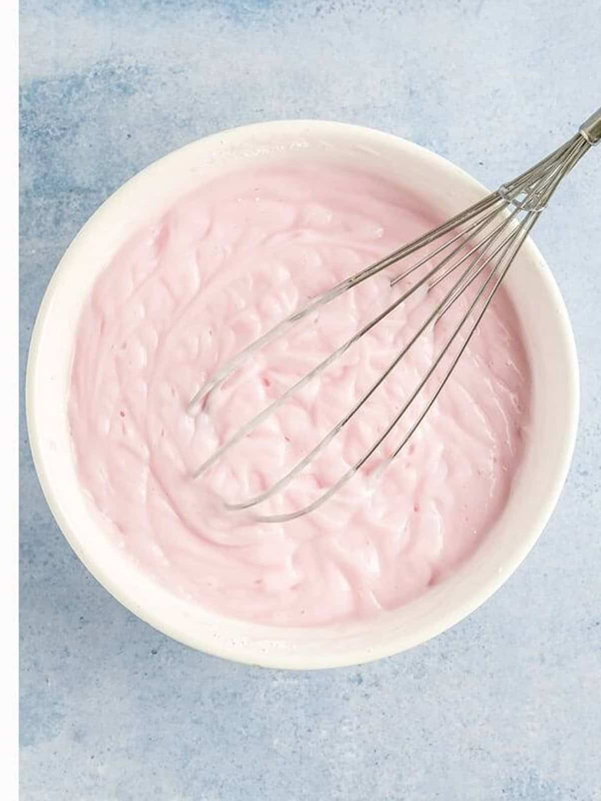 Smooth whisked pink frozen yogurt mixture in a bowl.