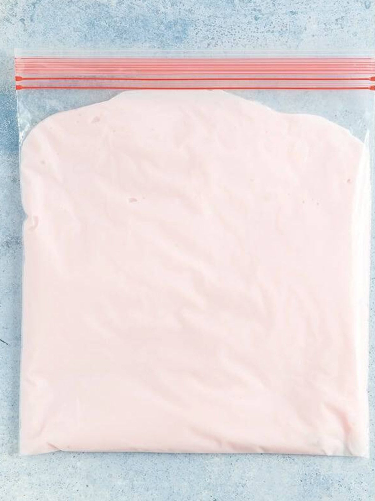 Frozen yogurt mixture pressed flat in a zip top freezer bag.