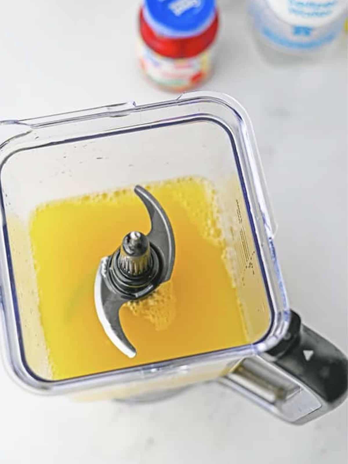 Pineapple juice and cream of coconut in a blender for fruit punch recipe.