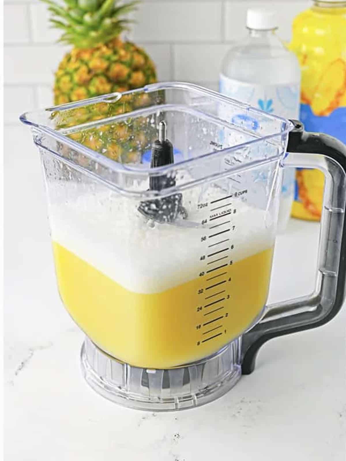Blended pineapple and coconut mixture in the blender for fruit punch recipe.
