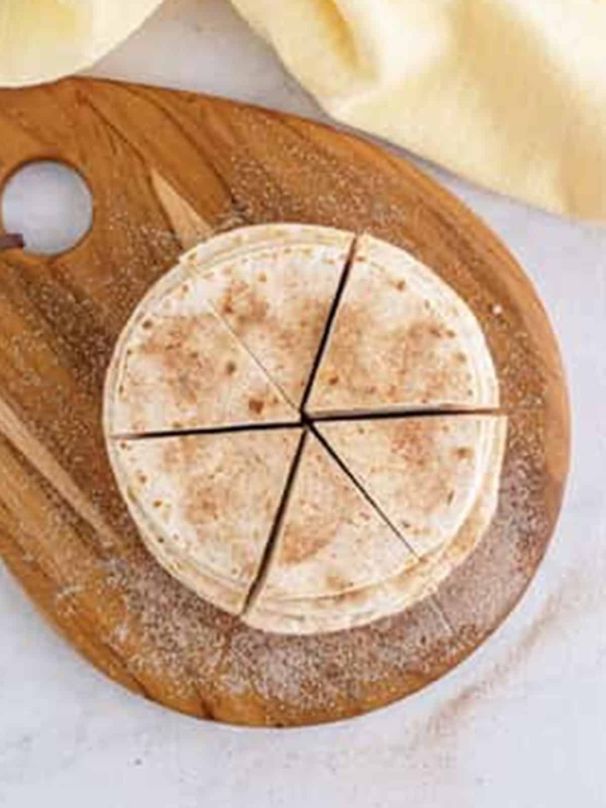 A stack of cinnamon sugar tortillas cut into six triangle wedges.