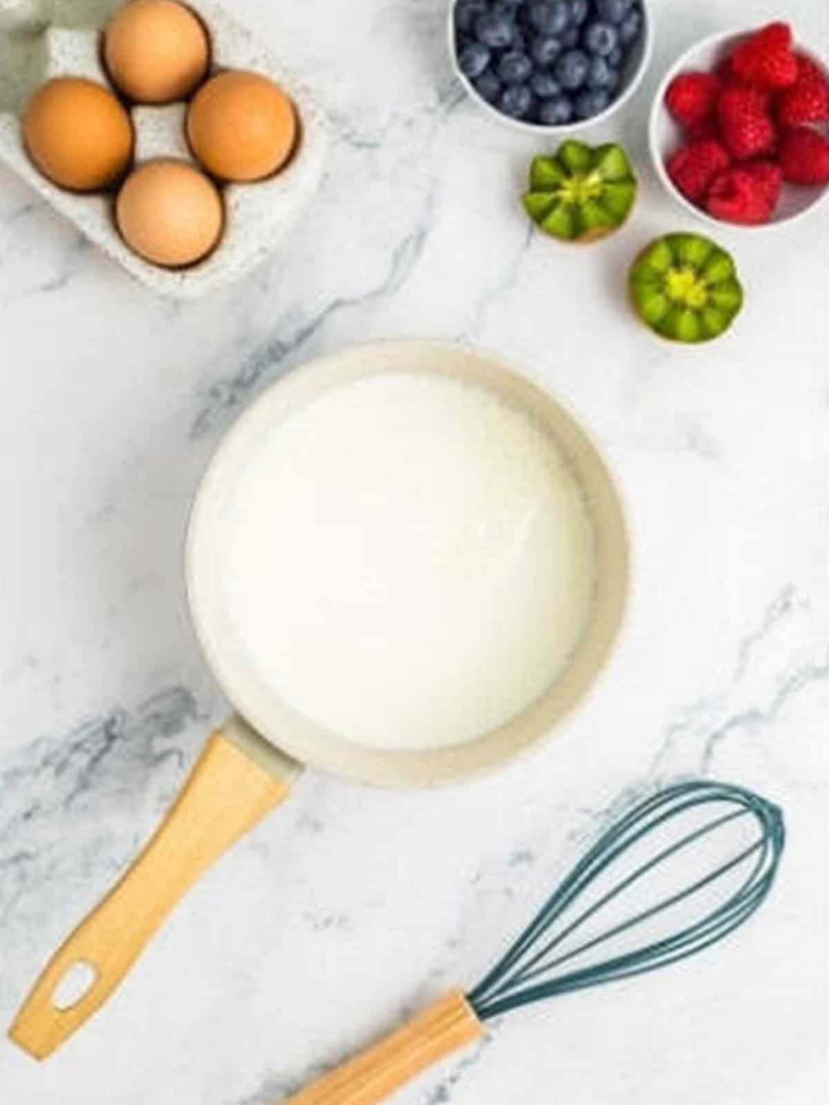 Whisking milk and sugar in a saucepan to start pastry cream for fruit tartlets.
