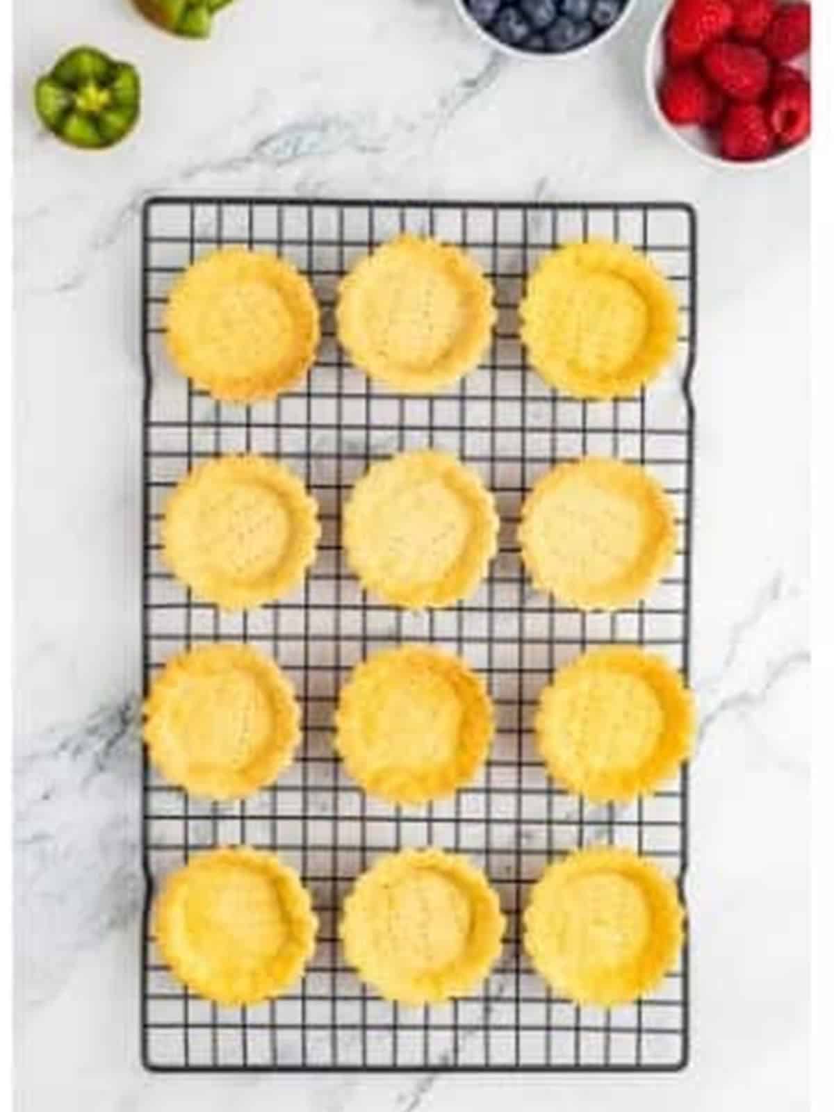 Baked mini tartlet shells cooling on a wire rack.