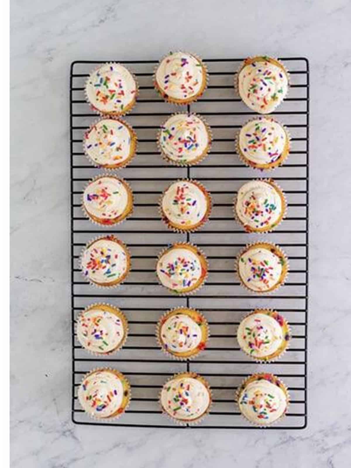 Frosted Funfetti Cupcakes topped with rainbow sprinkles.