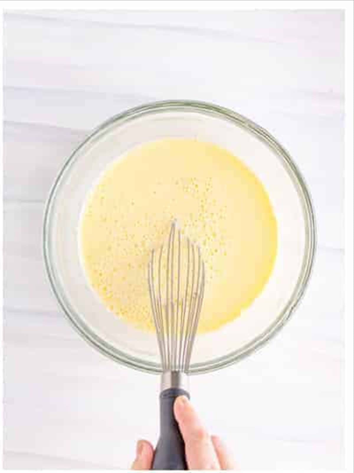 Whisking milk into the funnel cake recipe batter.