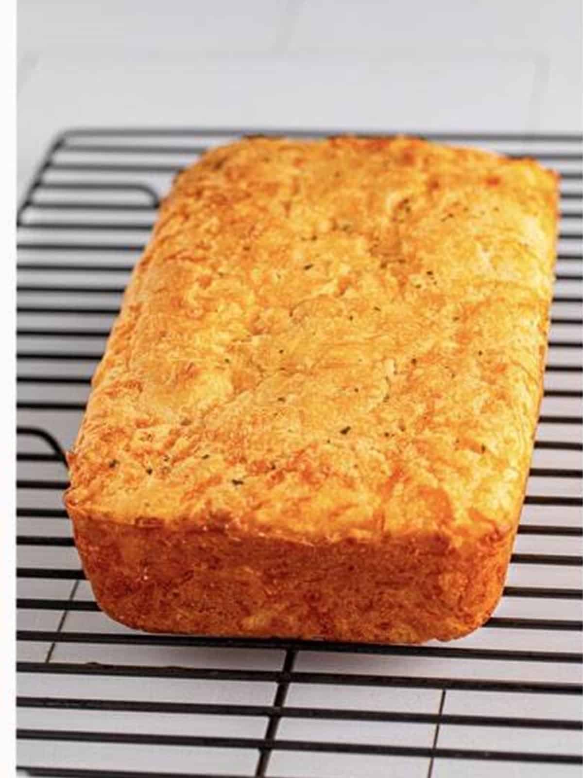A golden baked loaf of garlic cheese bread on a cooling rack.