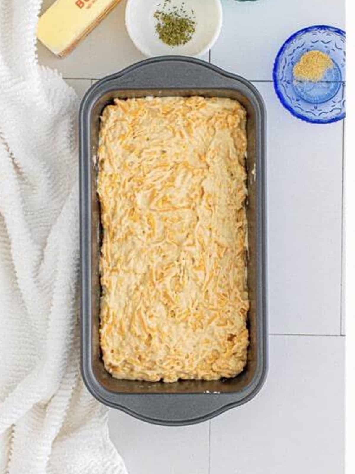 The cheese bread batter spread into a greased loaf pan.