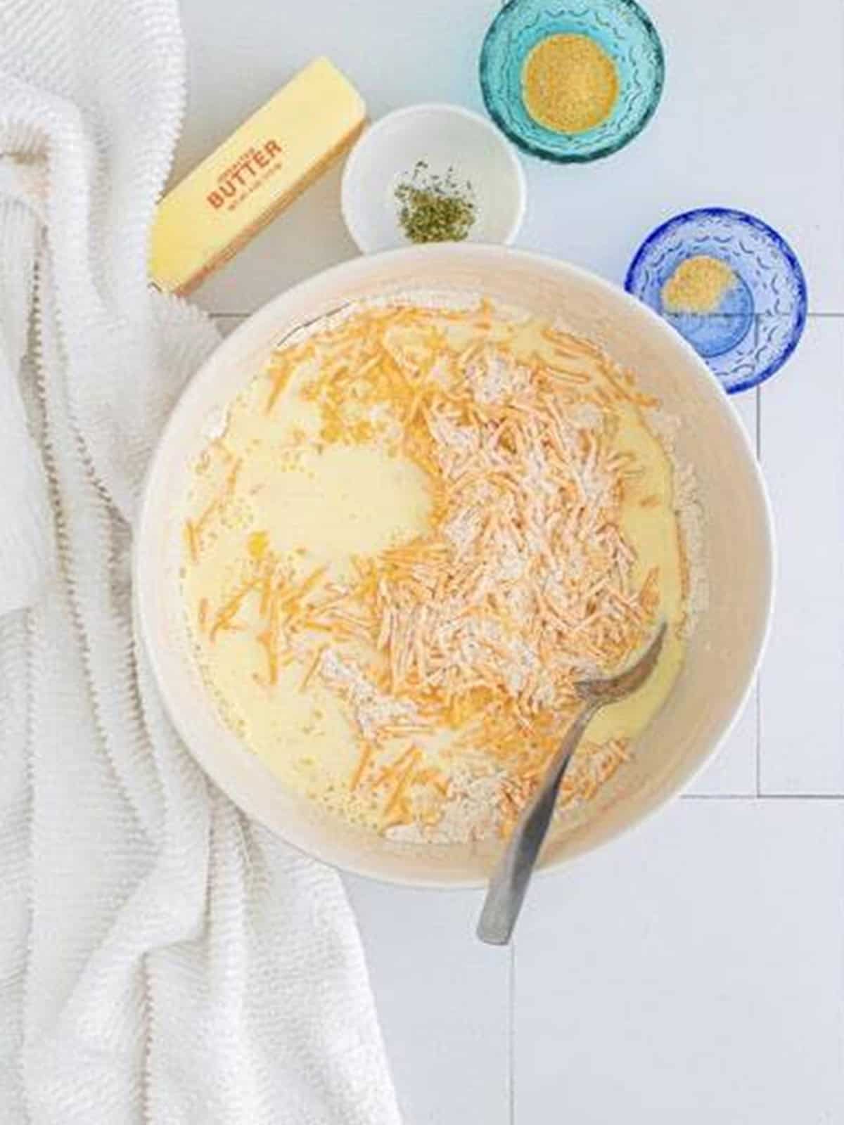 Milk, egg, and melted butter added to the cheese and flour mixture in the bowl.
