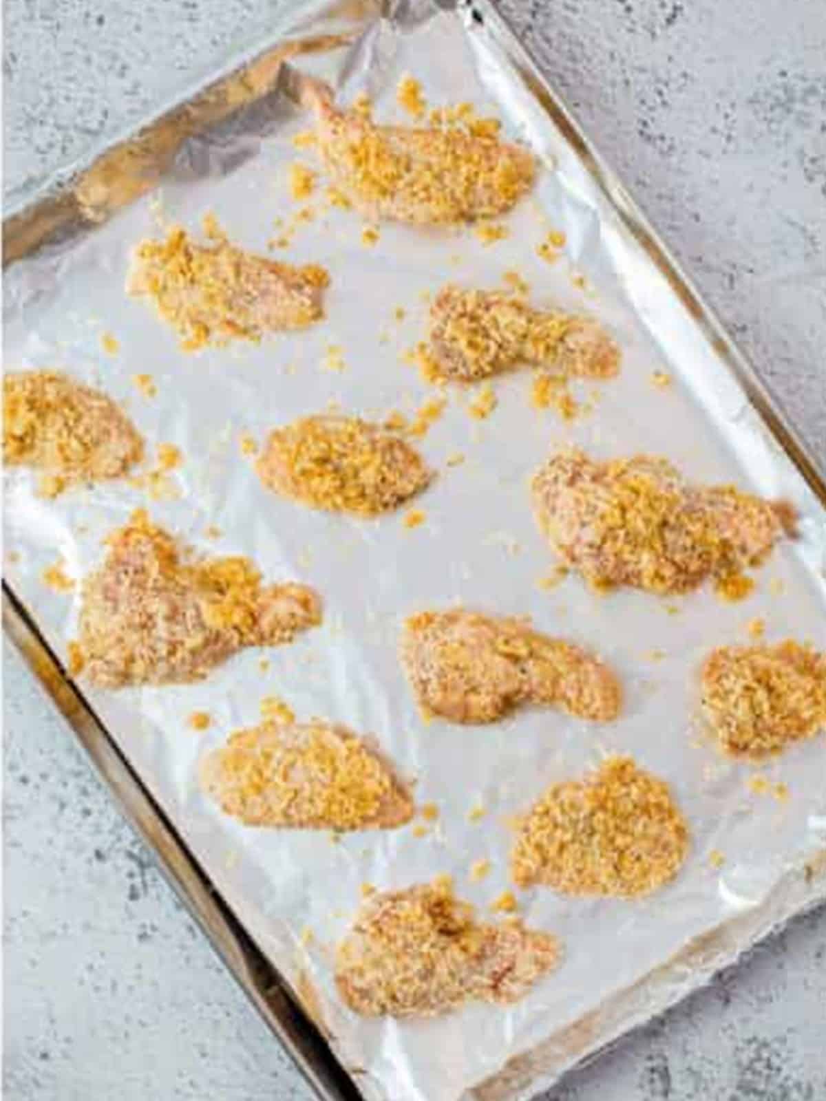 Coated garlic parmesan wings arranged on a parchment lined baking sheet.