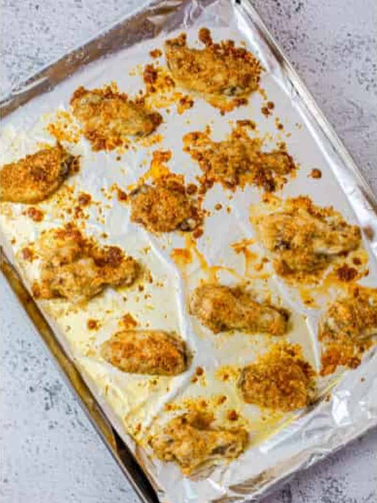 Golden brown baked garlic parmesan wings fresh from the oven on a baking sheet.