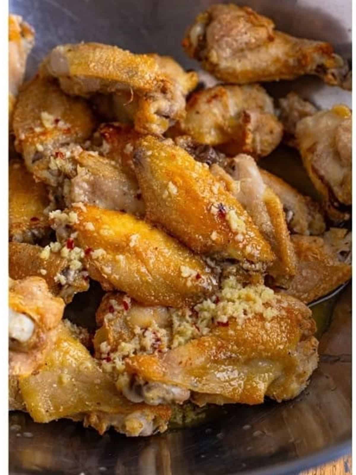Tossing the baked wings in garlic butter sauce for Garlic Parmesan Wings.
