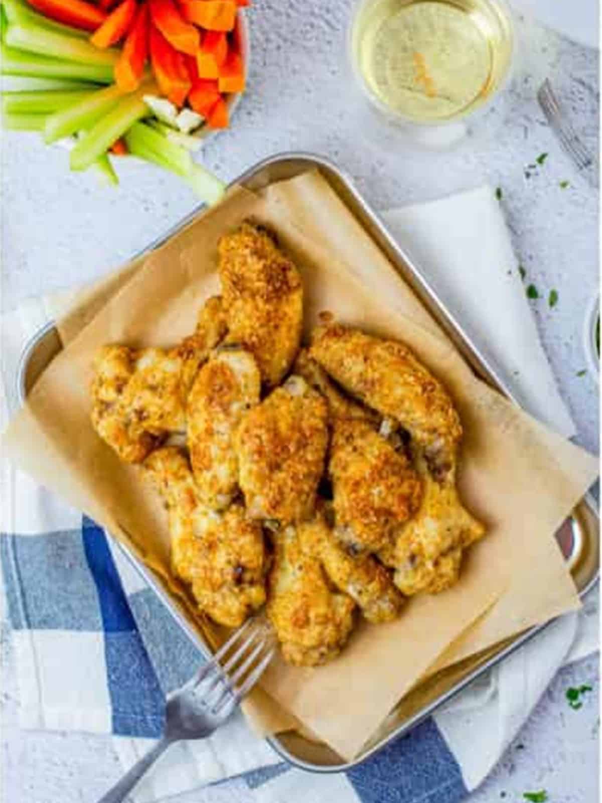 Garlic parmesan wings served in a dish with celery sticks and dip.