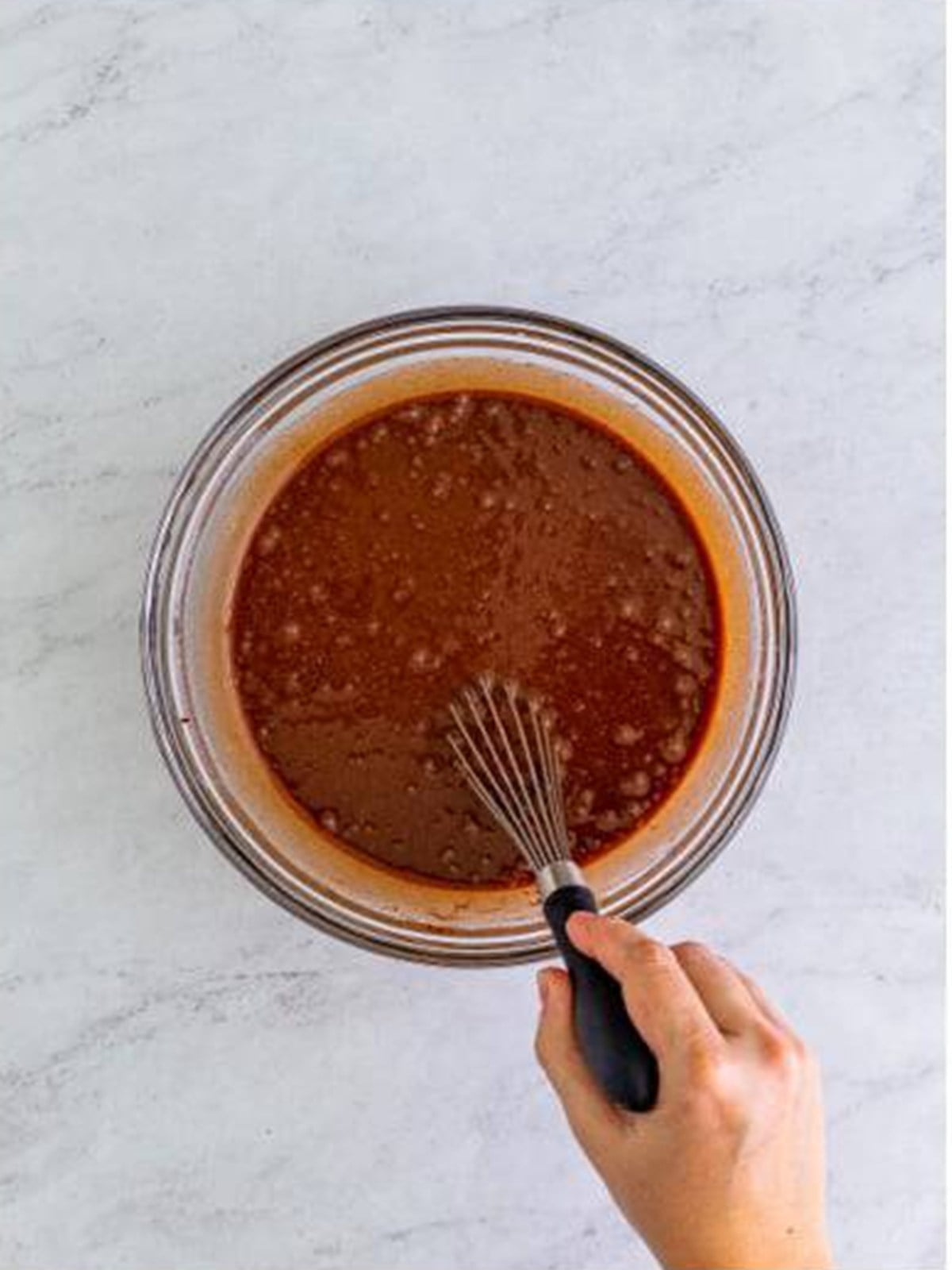 Whisking the chocolate cake batter in a glass bowl for German chocolate cake.