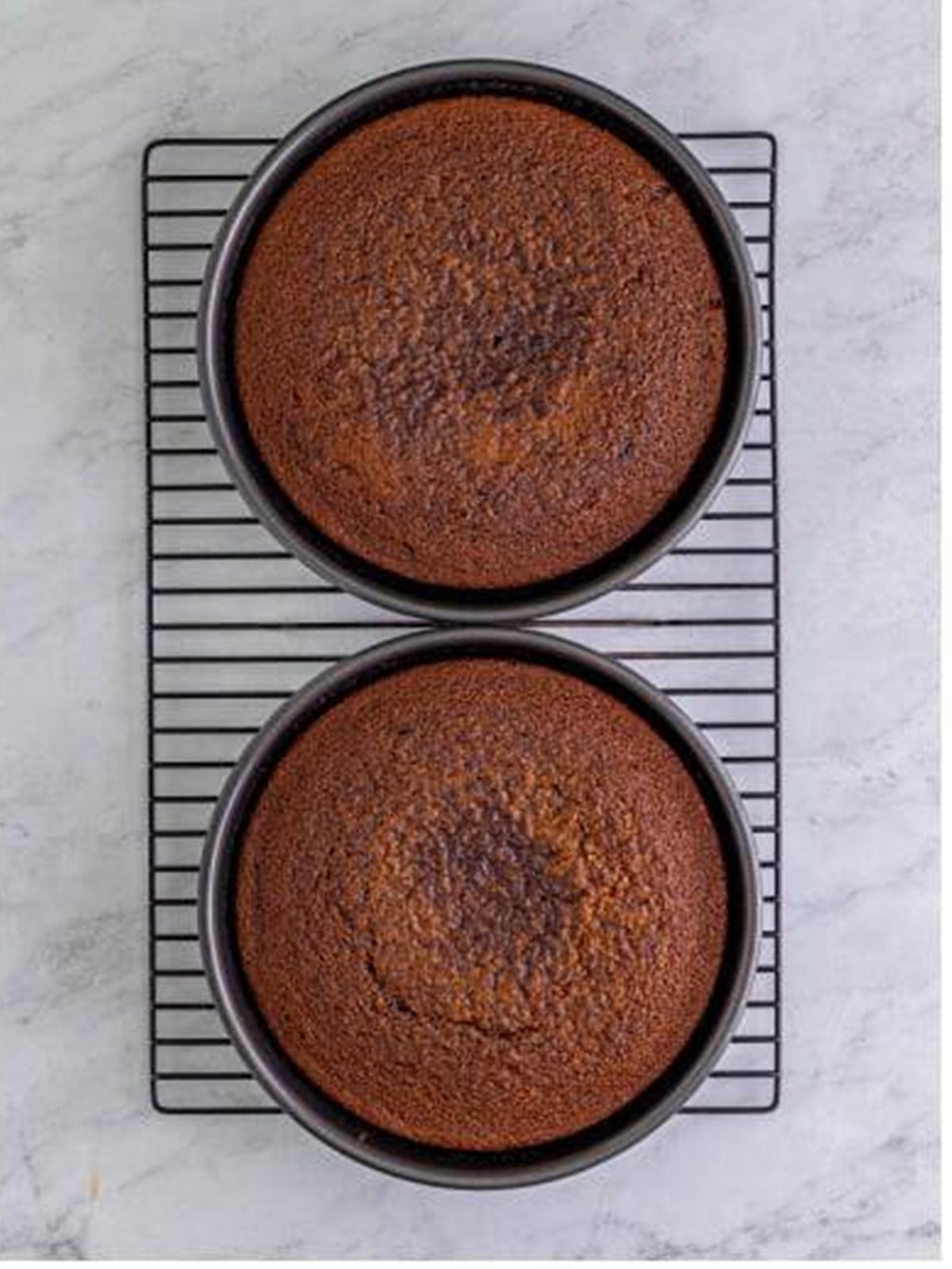 Two baked German chocolate cake layers cooling on a wire rack.