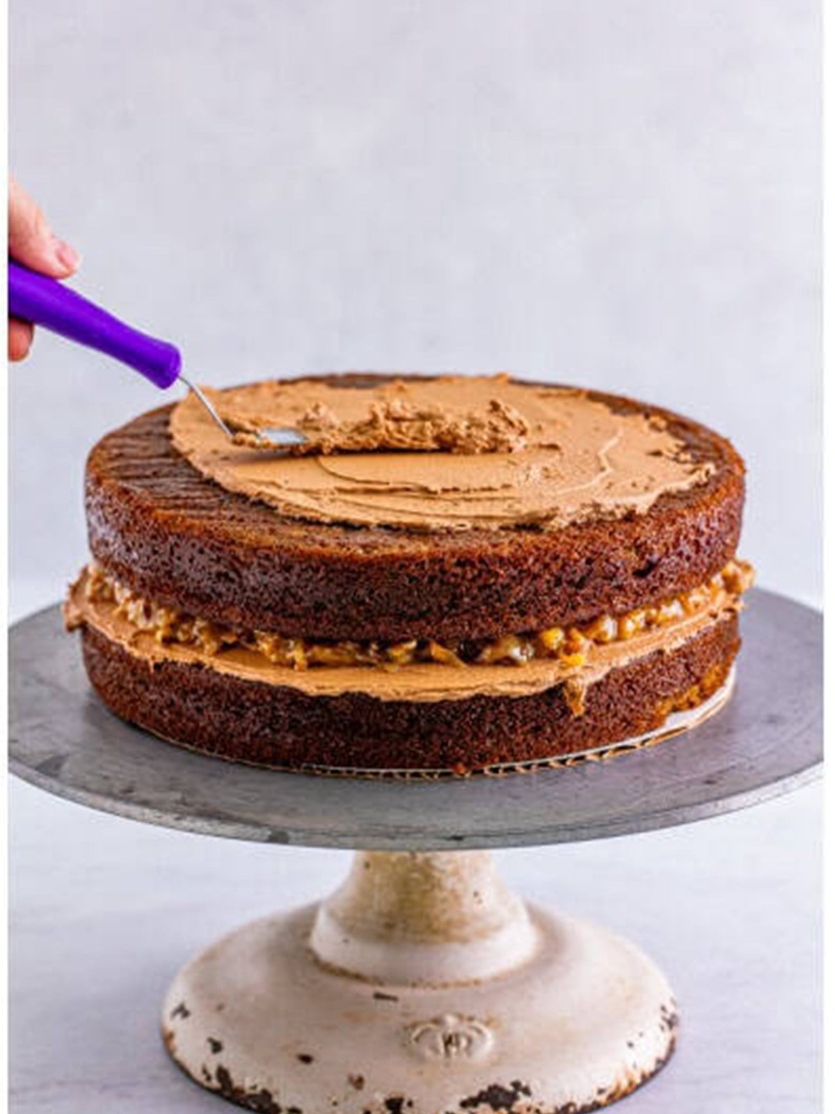 Stacking and filling German chocolate cake layers with coconut pecan frosting.