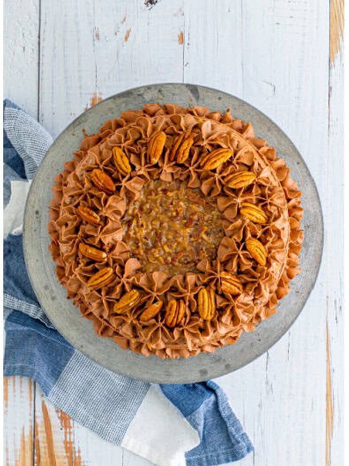 Finished frosted German chocolate cake topped with coconut pecan frosting and pecans.